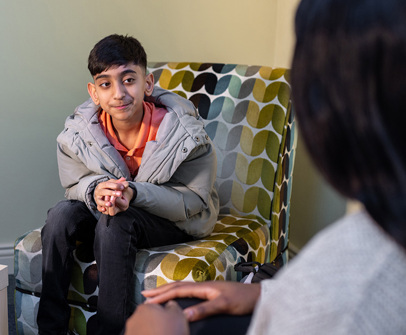 Photo of a young boy sitting in a chair having a conversation with a support worker